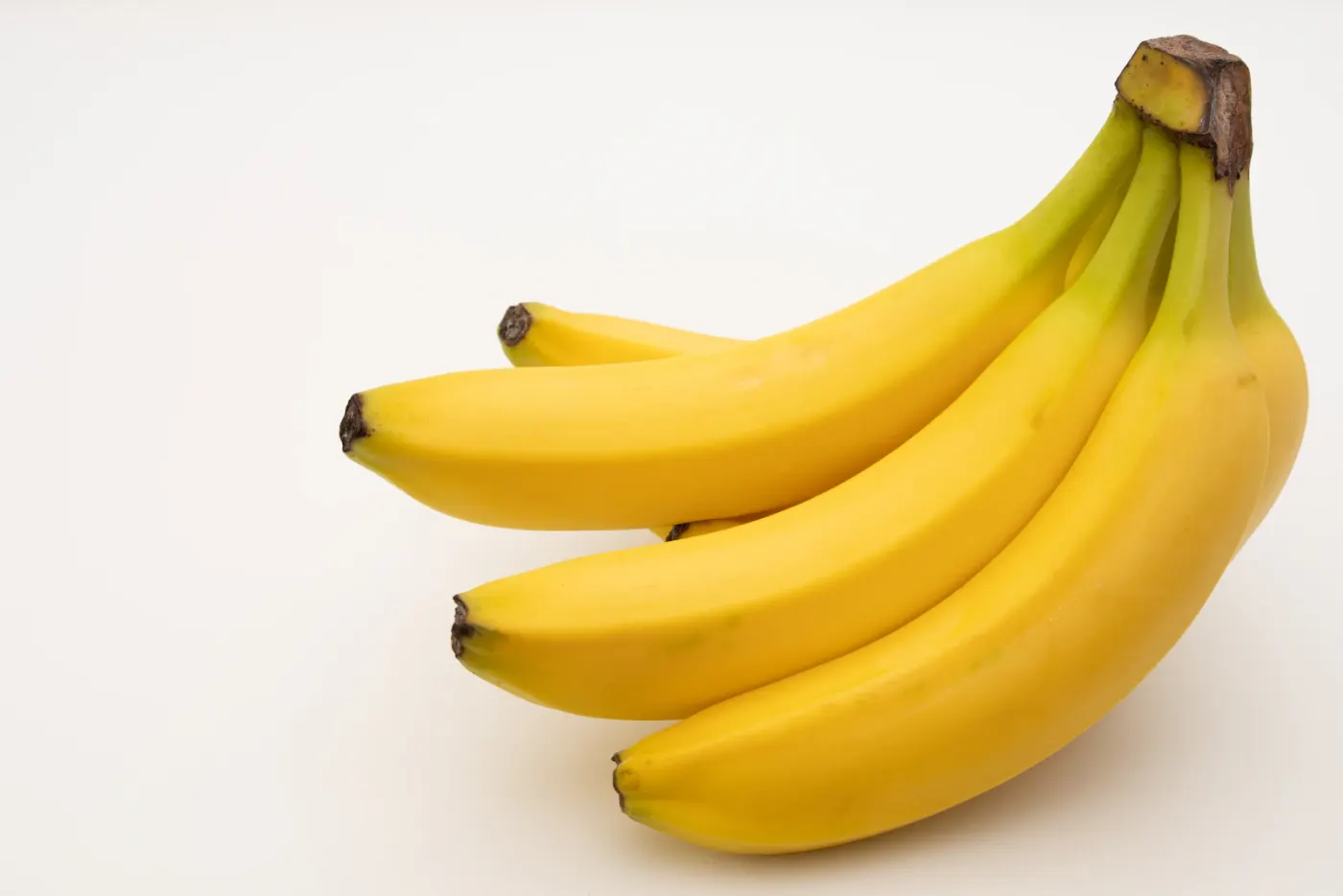 A bright yellow bunch of table bananas on a clean background